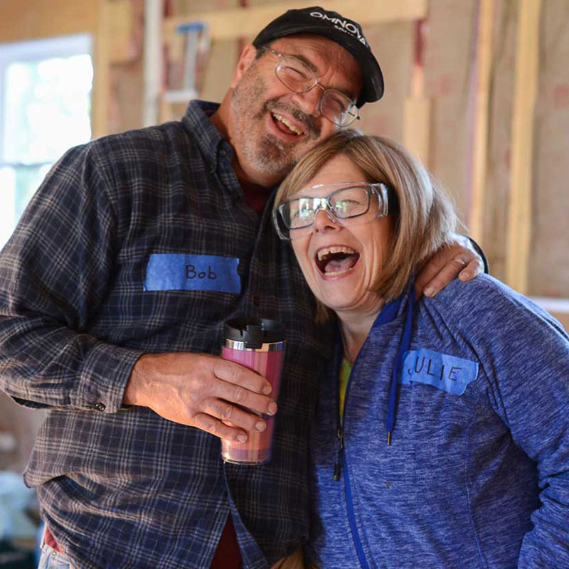 Two people smiling in a house that is freshly constructed.
