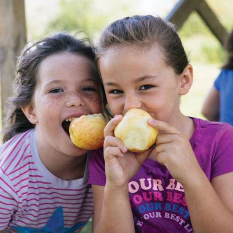 Two girls eating an apple. 